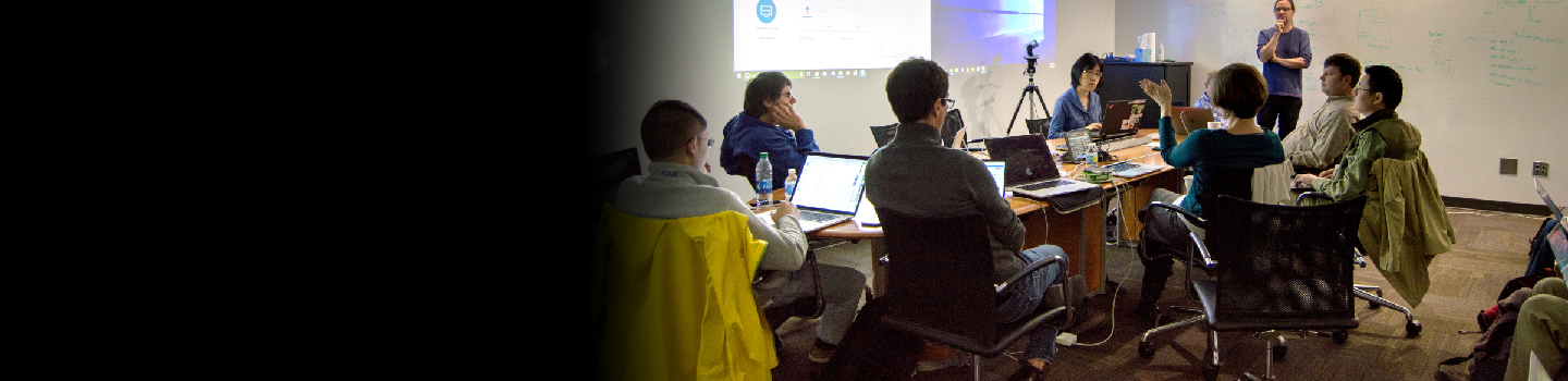 People sitting around a table looking at laptops.